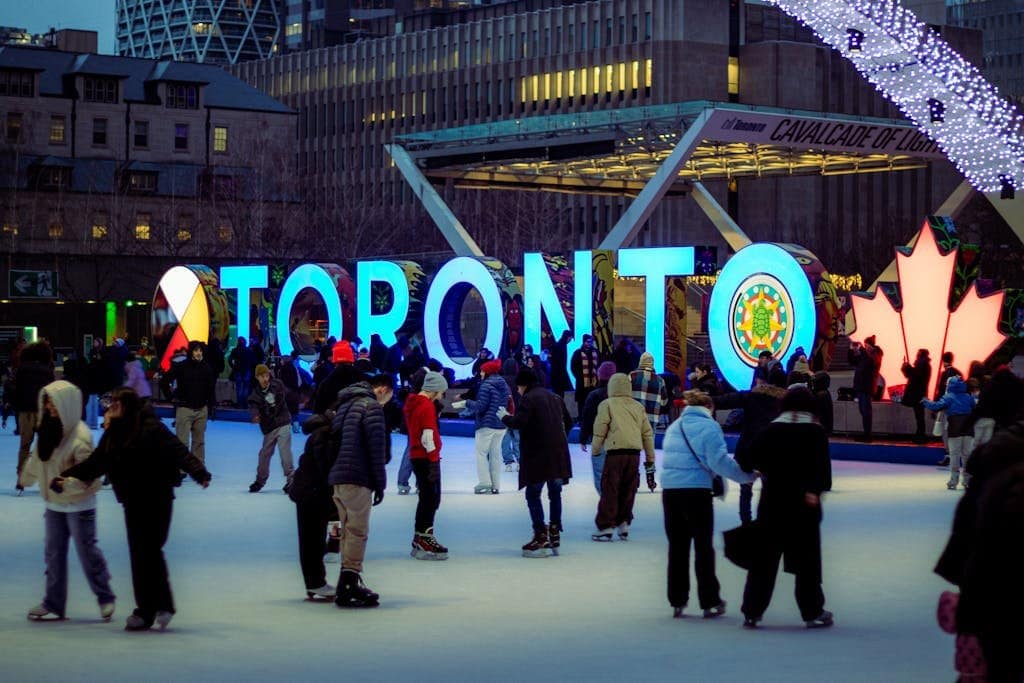 A lively ice skating scene with people enjoying winter at Toronto's illuminated sign.