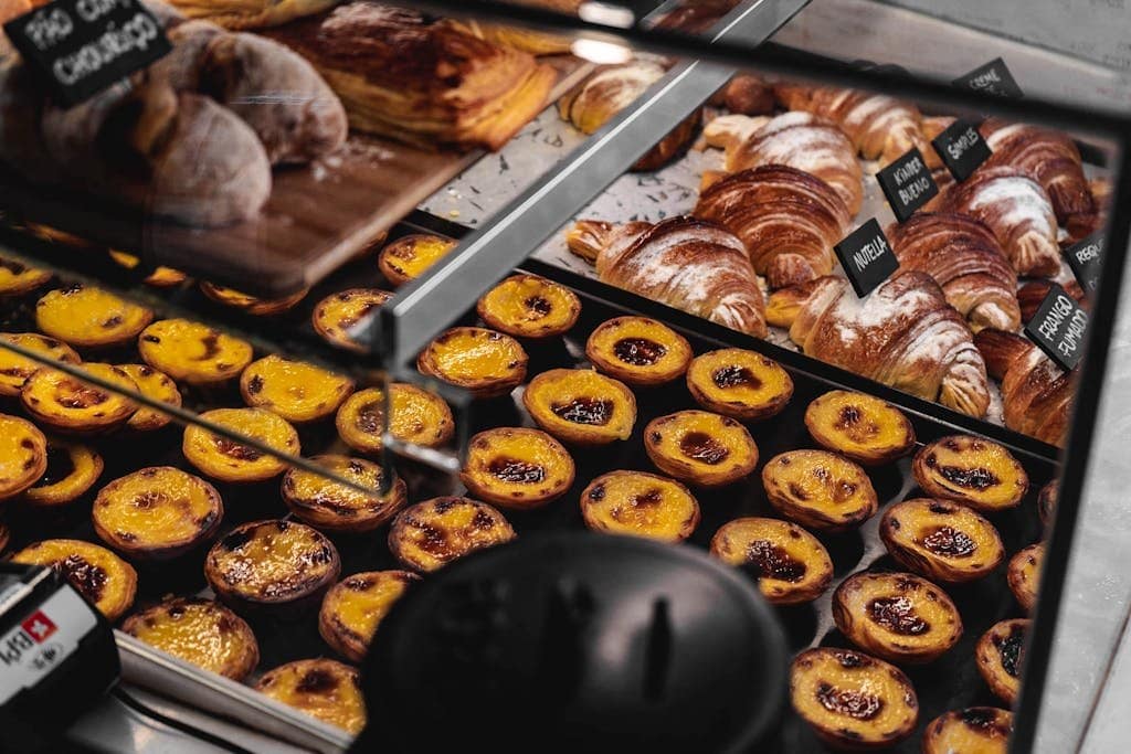 Showcase of pasteis de nata and croissants in a Lisbon bakery. Tempting treats on display.