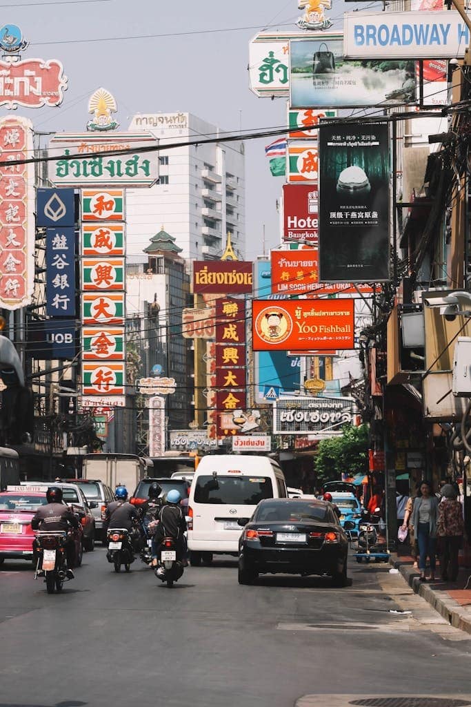 Street view of busy Bangkok Chinatown with vibrant signs and traffic.