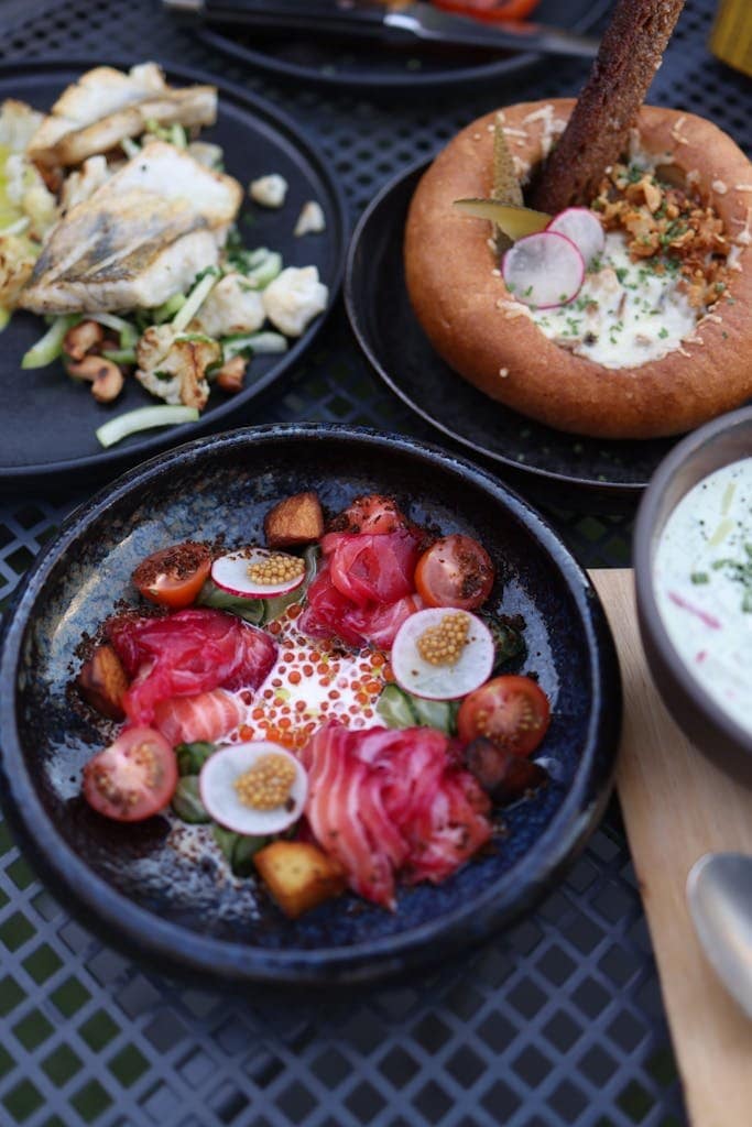 A gourmet seafood lunch featuring salmon, radishes, and caviar presented beautifully on plates.