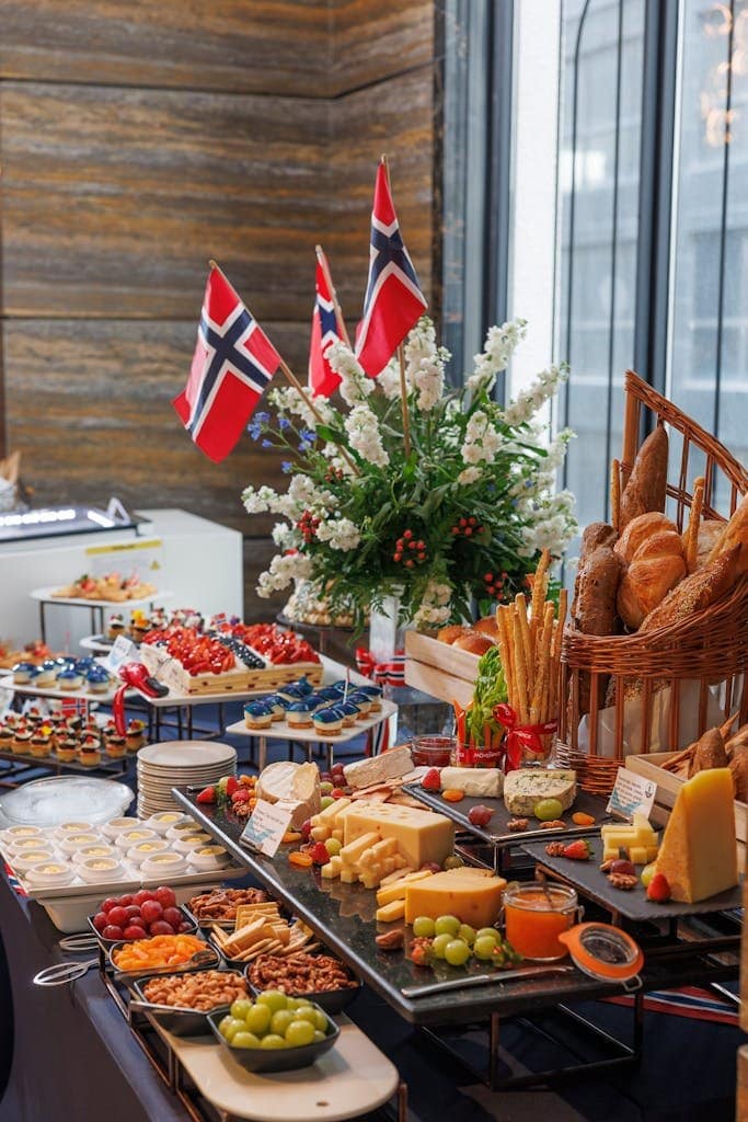 Lush buffet display featuring Norwegian flags, cheeses, fruits, and breads indoors.