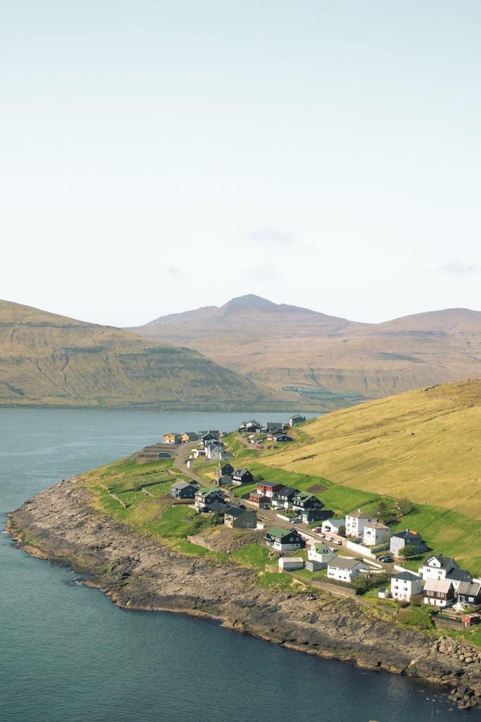 Stunning aerial view of a coastal village on the Faroe Islands surrounded by dramatic cliffs and ocean.