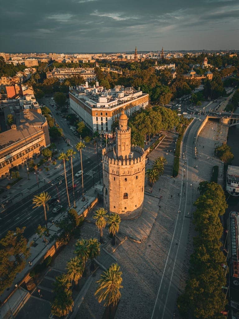 Stunning drone perspective of Torre del Oro surrounded by the vibrant cityscape of Seville, Spain.