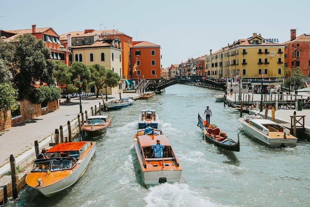 Vibrant canal scene in Venice with boats and classic architecture under a bright summer sky.